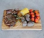 Close-up of a grilled steak with roasted vegetables on a wooden cutting board, perfect for BBQ themes.